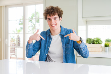 Young handsome man wearing casual denim jacket at home looking confident with smile on face, pointing oneself with fingers proud and happy.