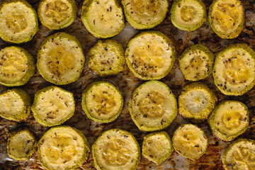 Background of a large number of baked zucchini pieces. Vegetarian dish.