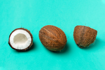 Ripe coconuts and half coconut on bright blue background, minimal composition, tropical fruit concept, flat lay, pop art