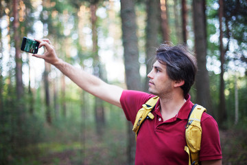 Hiker with backpack taking selfie in the woods