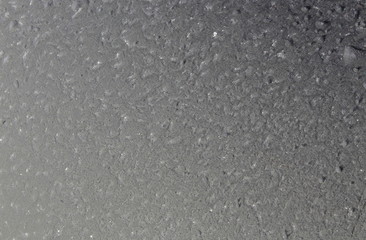 Frost in winter formed on a gray smooth surface