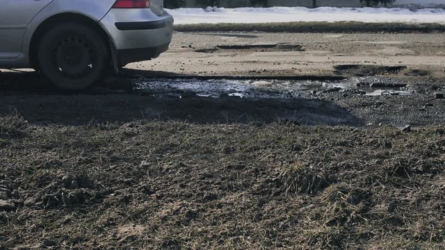 ars driving on a bad road surface with pits and puddles on a broken asphalt