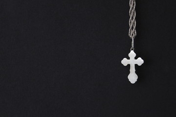 Fototapeta na wymiar silver orthodox cross hanging on a chain on a black background 