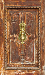 Precious wooden door aged by time. Bronze caller (gold).