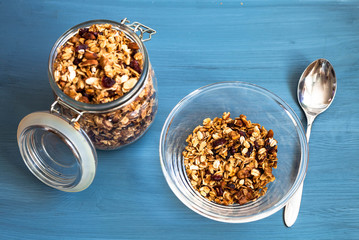 Homemade muesli in a plate on a blue background, healthy breakfast of oatmeal muesli, nuts, seeds and dried fruits