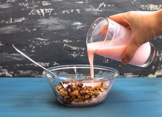 Homemade muesli with yogurt in a plate on a blue background, healthy breakfast of oatmeal muesli, nuts, seeds and dried fruits