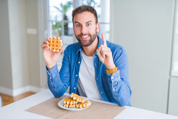 Handsome man eating sweet Belgian pancakes surprised with an idea or question pointing finger with happy face, number one