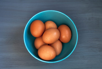 top view of eggs in a blue bowl on a blue wooden background