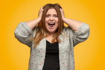 Angry overweight woman screaming and tearing out hair