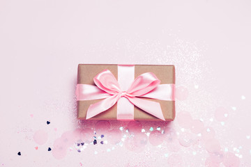Gift box and Pink confetti and stars and sparkles on pink background. Top view, flat lay. Bright and festive holiday background. For Christmas, New year, Mother's day, International woman's day