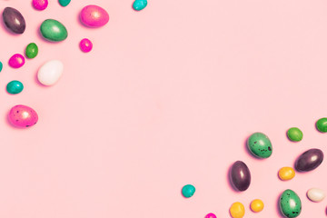 Easter frame made from colorful eggs and big chocolate egg flat lay on white background. Top view, copyspace for text.