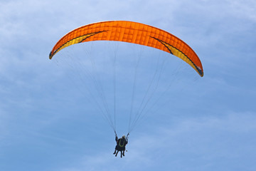 Tandem paraglider flying orange wing