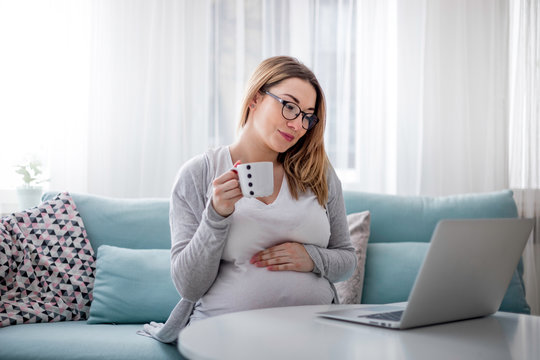 Pregnant woman working online with laptop at home, freelancing concept