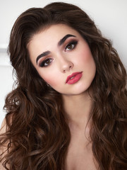Fototapeta premium Portrait of beautiful elegant woman with brown curly hair, trendy styling, beautiful makeup, glossy, smooth skin posing for makeup artist social network portfolio