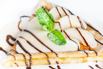 Thin delicious pancake with condensed milk on white