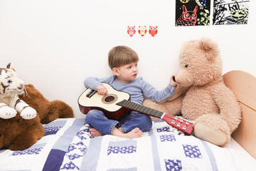 Ein dreijähriger Junge spielt auf einer Gitarre