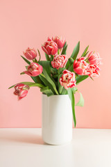 Bouquet of red tulip in vase on millennial pink.