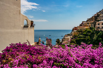 View of the village of Positano with fuchsia bougainvillea flowers, Campania - Italy