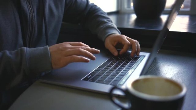 Digital technology, software development concept. Close-up hands - software developer (programmer) typing code for mobile device. Business office concept with cup of coffee and wooden table. Freelance