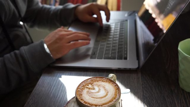 Digital technology, software development concept. Close-up hands - software developer (programmer) typing code for mobile device. Business office concept with cup of coffee and wooden table. Freelance