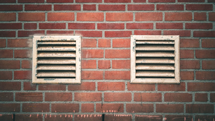 A brick wall with two vents