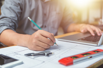 Hands of architect or engineer using pencil with blueprint on desk in office.Team of architects engineer discussing and check documents and business workflow.Construction concept.