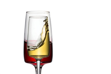 a glass of white wine with a high splash on the background of another with red
