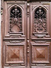 Wooden door of a building on the street with an iron decorative ornament. Old Tbilisi architecture