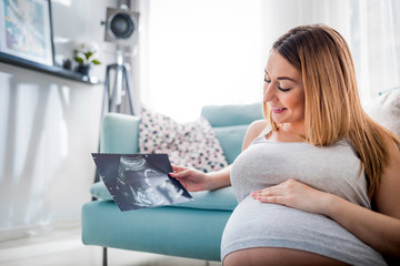 Pregnant woman looking her baby on ultrasound image, usg photo