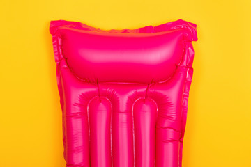 pink swim mattress on a yellow background, concept of summer vacation at sea