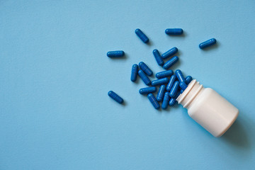 Assorted pharmaceutical medicine pills, tablets and capsules and bottle on blue background. Drugs and various narcotic substances. Copy space for text. Stock photo for design