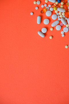Assorted pharmaceutical medicine pills, tablets and capsules and bottle on red background. Drugs and various narcotic substances. Copy space for text. Stock photo for design