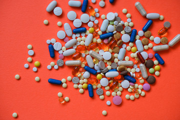 Fototapeta na wymiar Assorted pharmaceutical medicine pills, tablets and capsules and bottle on red background. Drugs and various narcotic substances. Copy space for text. Stock photo for design