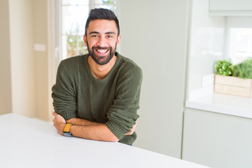 Handsome hispanic man wearing casual sweater at home happy face smiling with crossed arms looking...