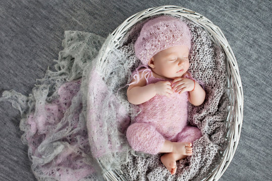 Beautiful little newborn girl 1 month sleeps in a wattled basket