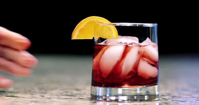 Close up of hand placing a mixed cocktail on bar