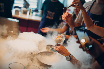 Woman pouring caramel syrup over  ice cream made with liquid nitrogen.