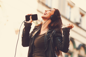 Young woman enjoys music on the street and dancing