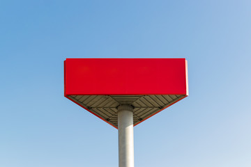 Empty red billboard with copy space on the background of a blue sky. Red mockup with place for your text.