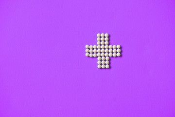 Obraz premium Medical cross laid out medicines, white tablets on a blue background. Pharmacology and medicine struggle for health. Drug addiction. Treatment of various diseases