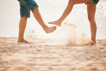 young couple playing with sand. Summer lifestyle. feet in the sand on the beach