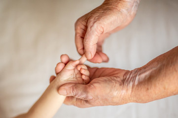 Great-grandmother touching little baby foot, the concept of a family and a new life. into a selective focus