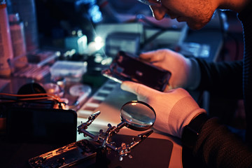 The technician carefully examines the integrity of the internal elements of the smartphone in a modern repair shop