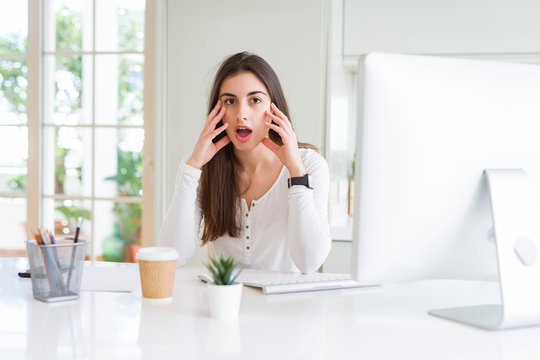 Beautiful young woman working using computer afraid and shocked with surprise expression, fear and excited face.