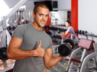 Fototapeta na wymiar Portrait of muscular guy lifting dumbbells