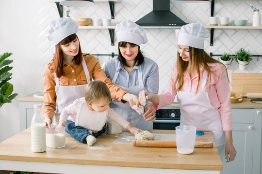 Two sisters, grandmother and little baby daughter cooking holiday pie in the kitchen to Mothers day, casual lifestyle photo series in real life interior