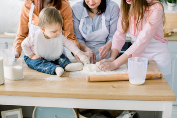 Portrait of Grandmother with her daughters and granddaughter together making dinner at the kitchen. Mothers Day concept.