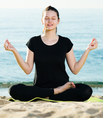 Adult female in black T-shirt is sitting and practicing asana