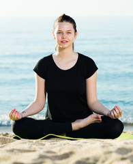 Fototapeta na wymiar Girl in black T-shirt is sitting and doing meditation