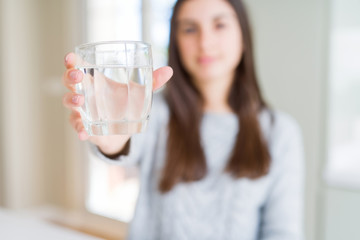 Beautiful young woman drinking a fresh glass of water with a confident expression on smart face thinking serious